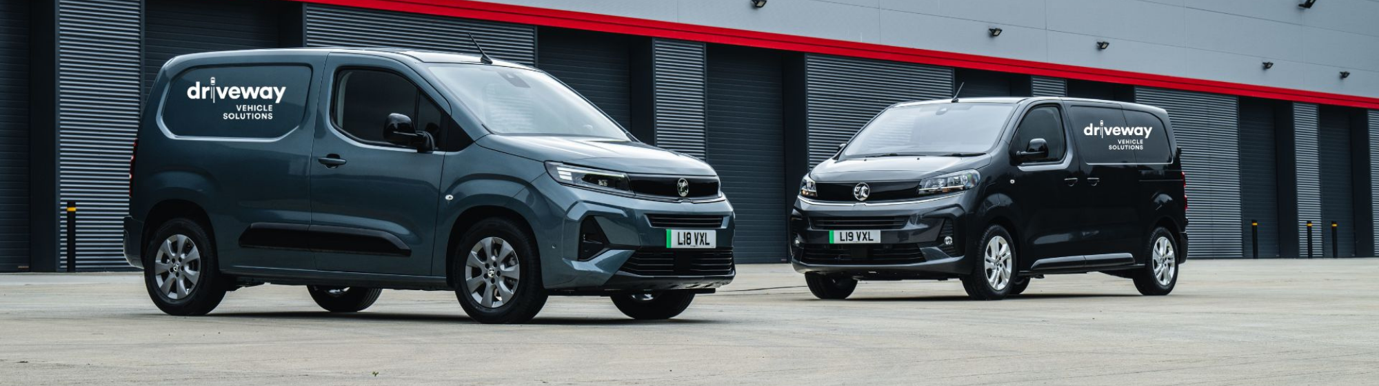 Two Grey Vans Parked Outside Warehouse Building