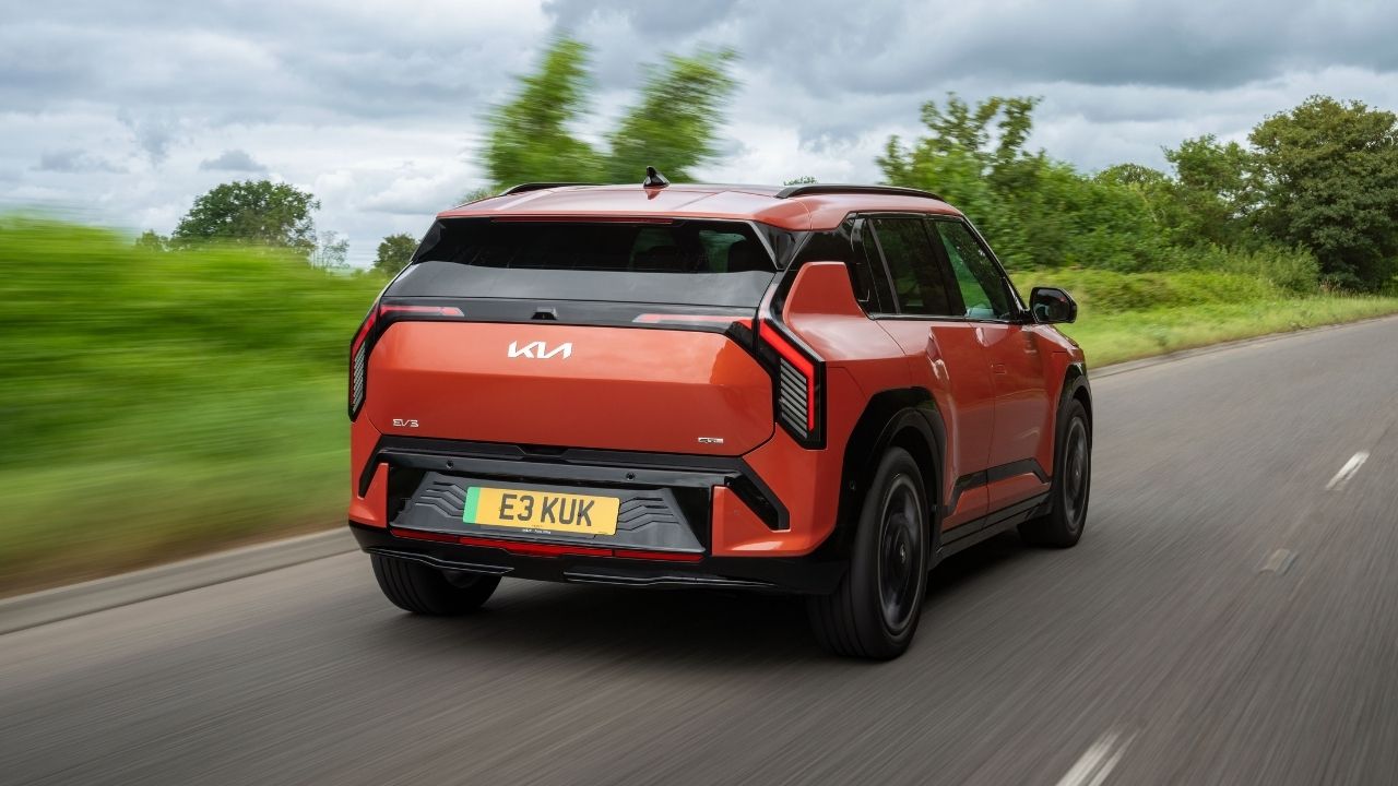 Orange Kia SUV Rear View Driving Down Country Road