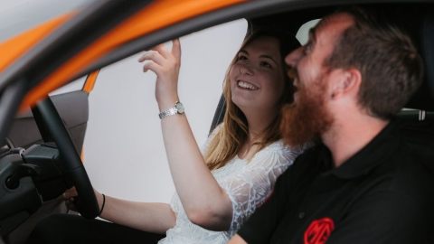 Man And Woman Sat In Car Looking At Rear View Mirror