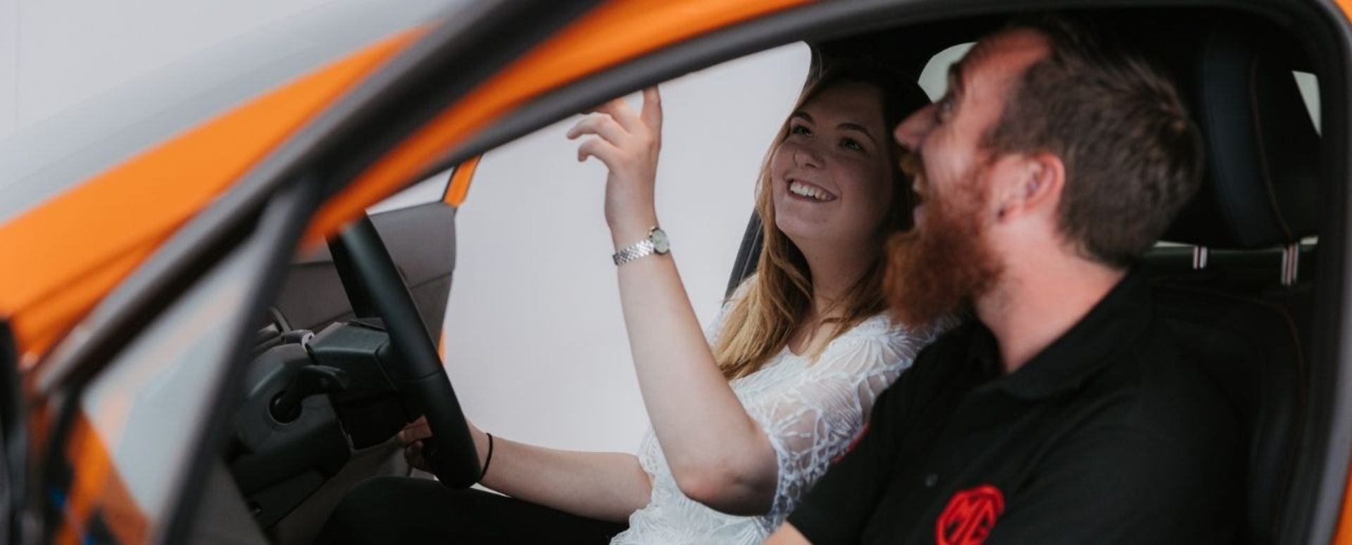Man And Woman Sat In Car Looking At Rear View Mirror
