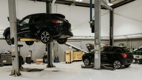 2 Black Cars On Lifts In a Workshop