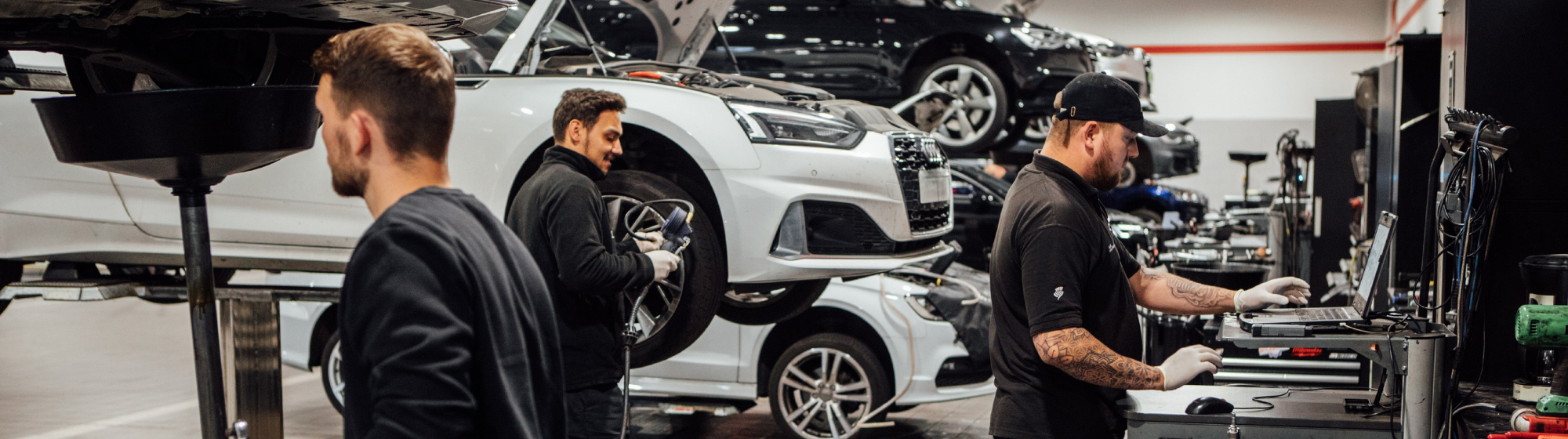 Three Colleagues Working in Vehicle Workshop