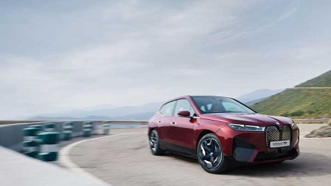 Red BMW iX, driving along coastal road