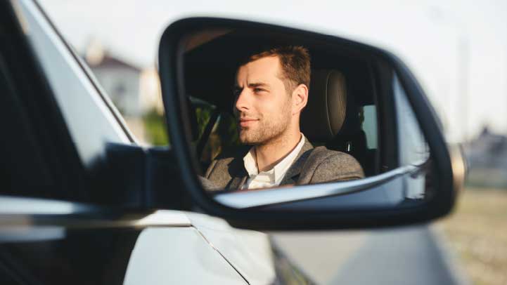 Wing Mirror Reflection of a Person Driving a Vehicle